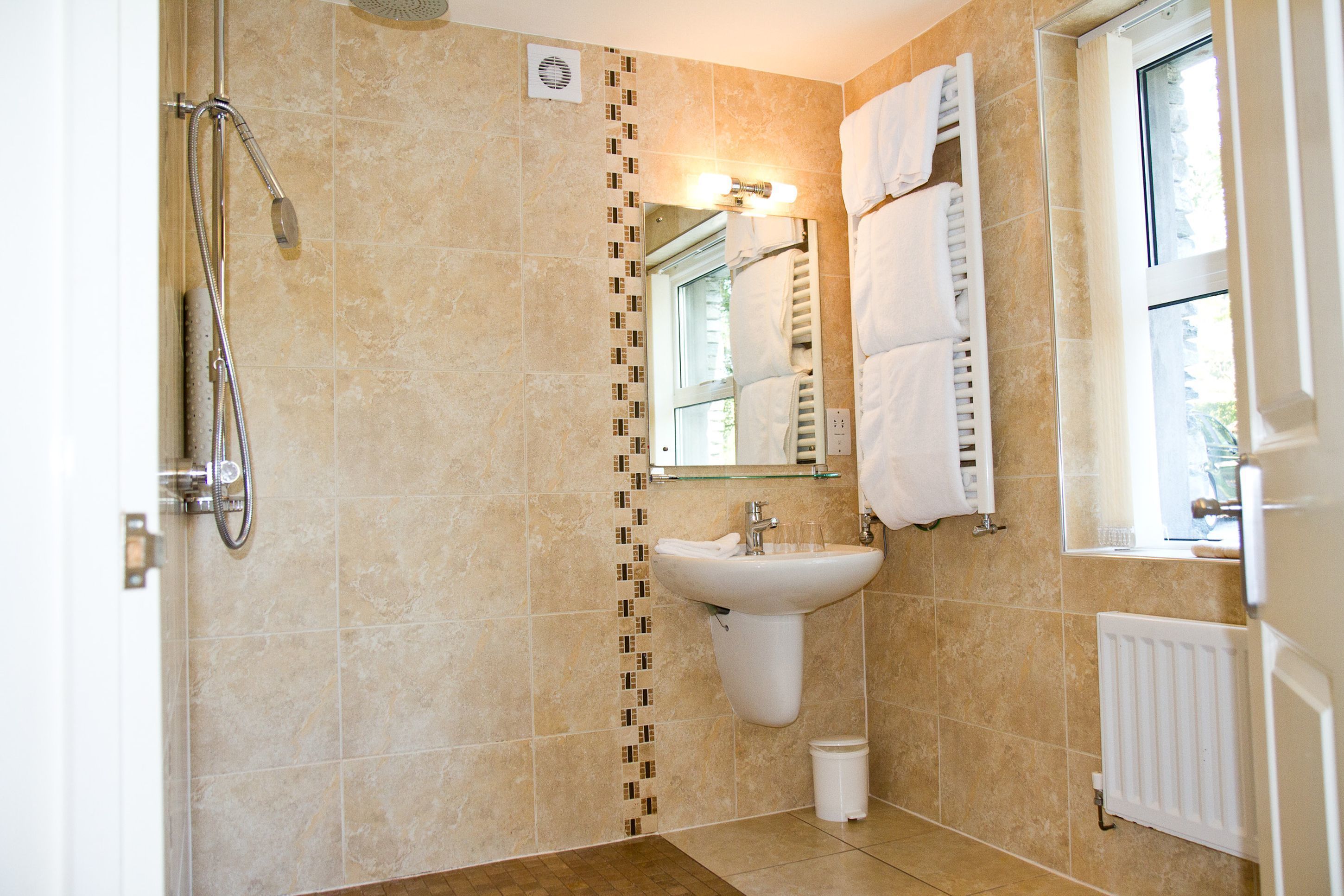 Un baño con ducha, lavamanos y espejo.