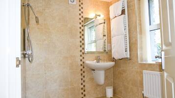 Un baño con ducha, lavamanos y espejo.