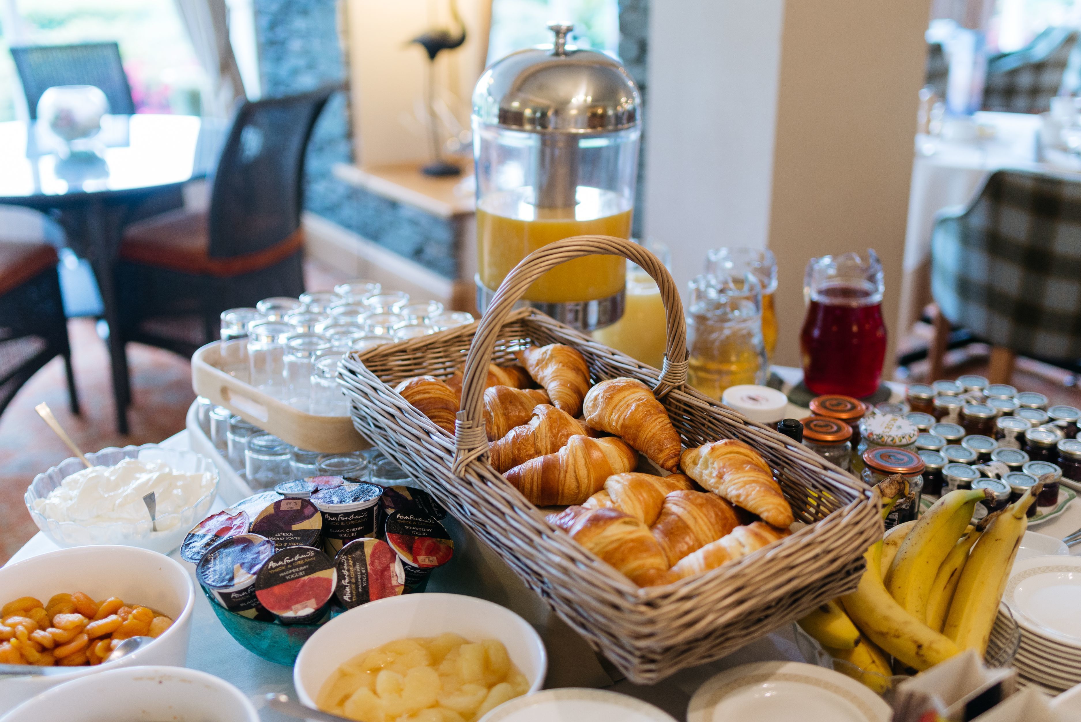 Un buffet della colazione con croissant, frutta e diverse marmellate.