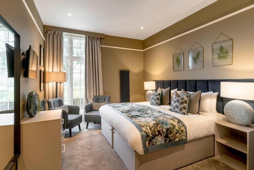 A modern bedroom with a large bed, a desk, and a chair. There are three framed pictures on the wall.
