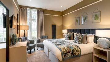A modern bedroom with a large bed, a desk, and a chair. There are three framed pictures on the wall.