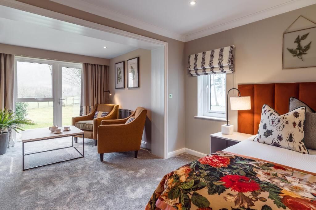 A hotel room with a bed, a sofa, a coffee table, a lamp, and a window with curtains.