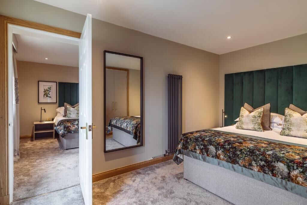 A bedroom with a large bed, a headboard, a mirror, a bedside table, and a nightstand.