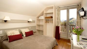 Et soveværelse med seng, sengeborde, en garderobe, en balkon med udsigt og en vase med blomster.
