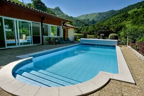 Una piscina al aire libre, sombrillas, sillones reclinables de piscina