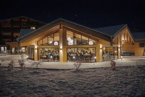 A modern building with large windows and a snow-covered ground. - Hôtel Club le Crêt (Morzine)