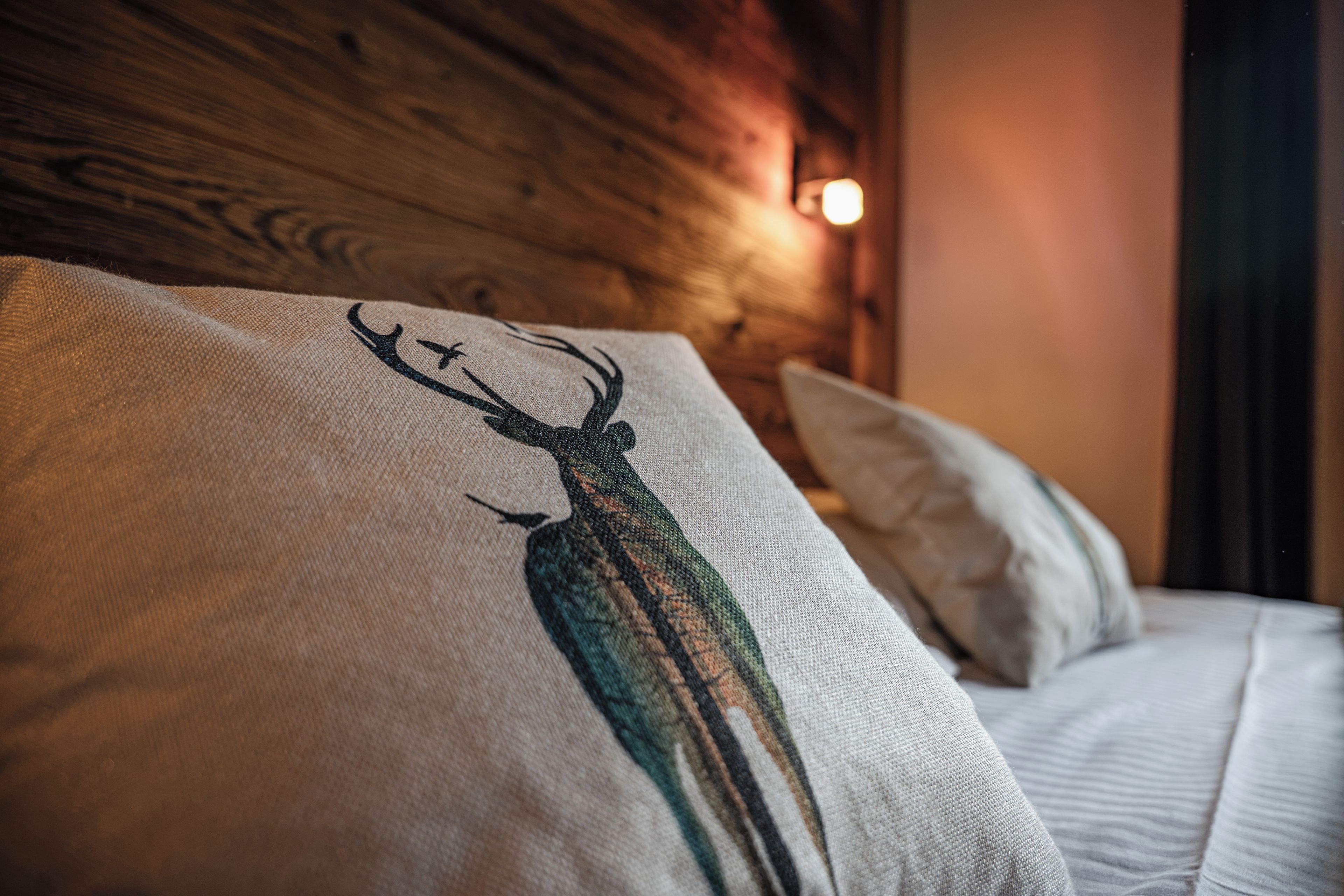 A bed with a pillow featuring a deer design.