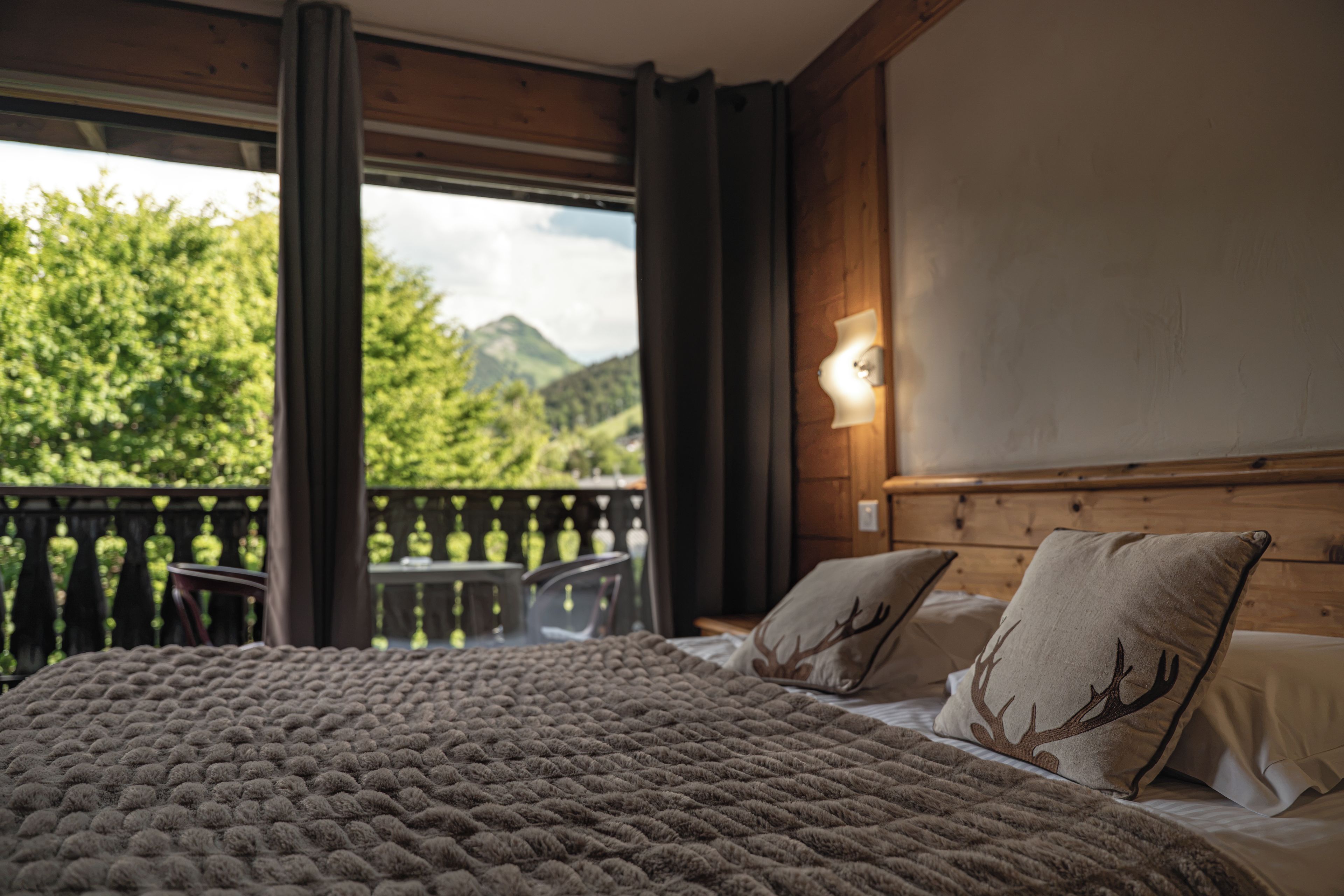 A bedroom with a bed, a nightstand, and a view of a balcony with a table and chairs.