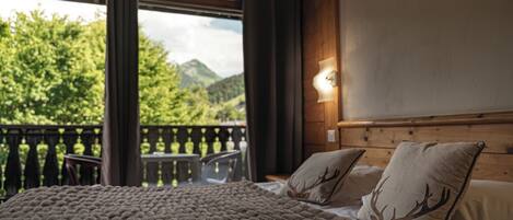 A bedroom with a bed, a nightstand, and a view of a balcony with a table and chairs.