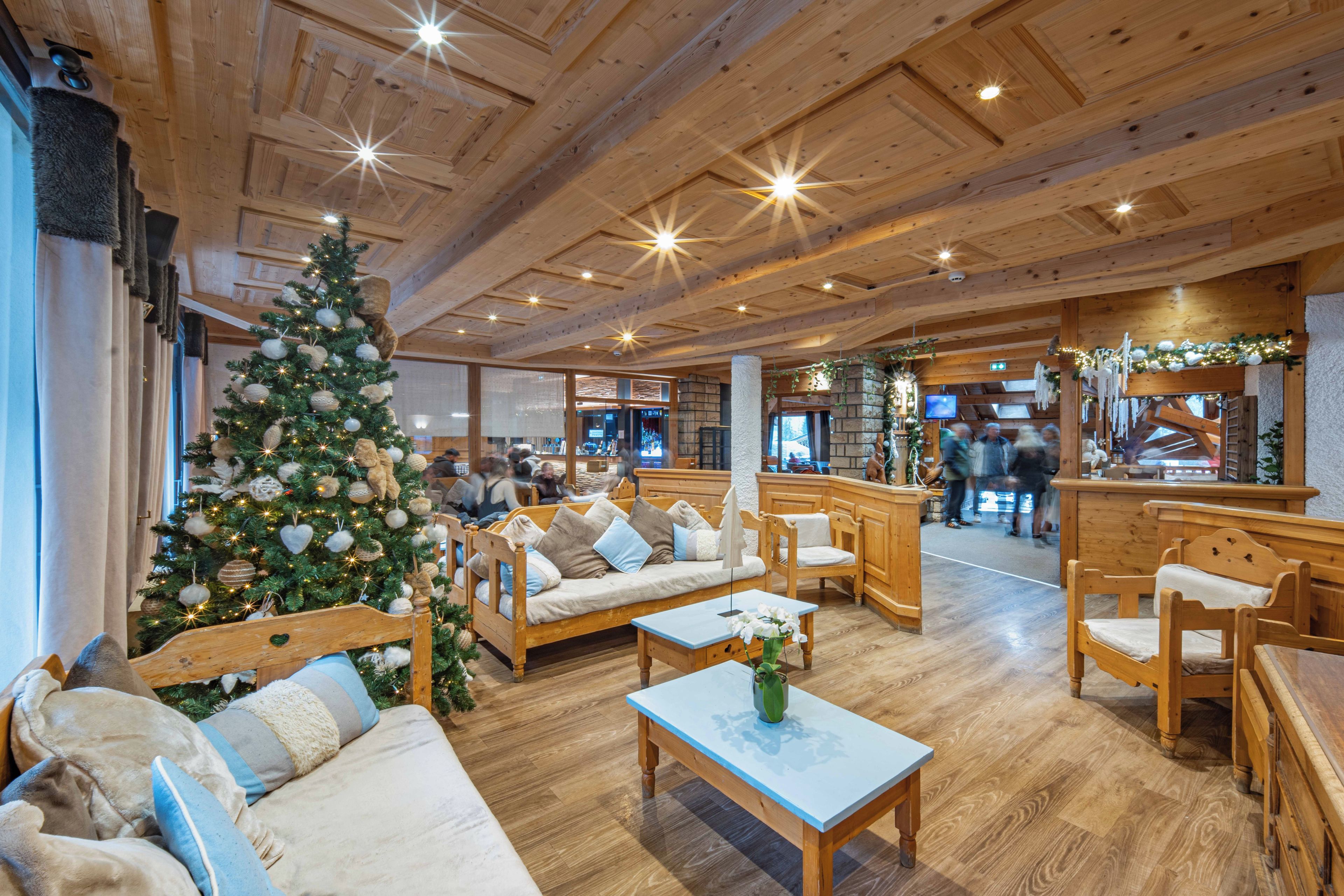Eine gemütliche Lobby mit einem großen Weihnachtsbaum, Holzmöbeln und einem Kamin.