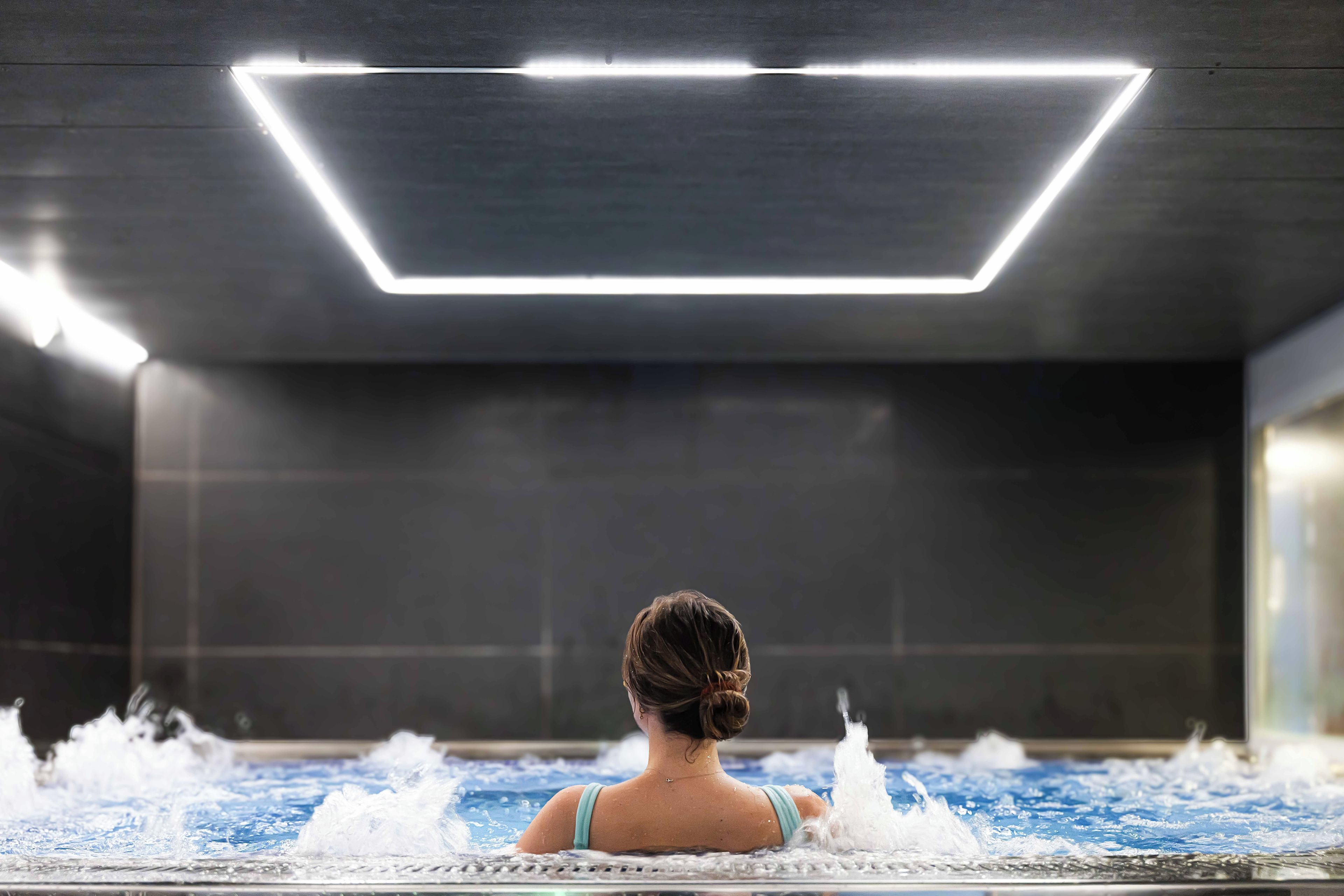 A person in a spa bath with a modern ceiling light fixture.