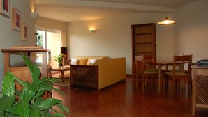 A spacious living area with a sofa, dining table, chairs, and a bookshelf. - La Residence du Rova (Antananarivo)