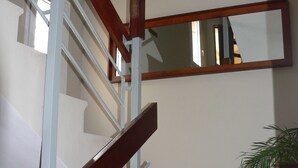 A staircase with a wooden handrail and beige steps, leading to a landing with a potted plant. - La Residence du Rova (Antananarivo)