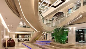 A multi-level atrium with a central staircase, glass railings, and a seating area with sofas and a bar. - Radisson Blu Hotel Liuzhou (Liuzhou)
