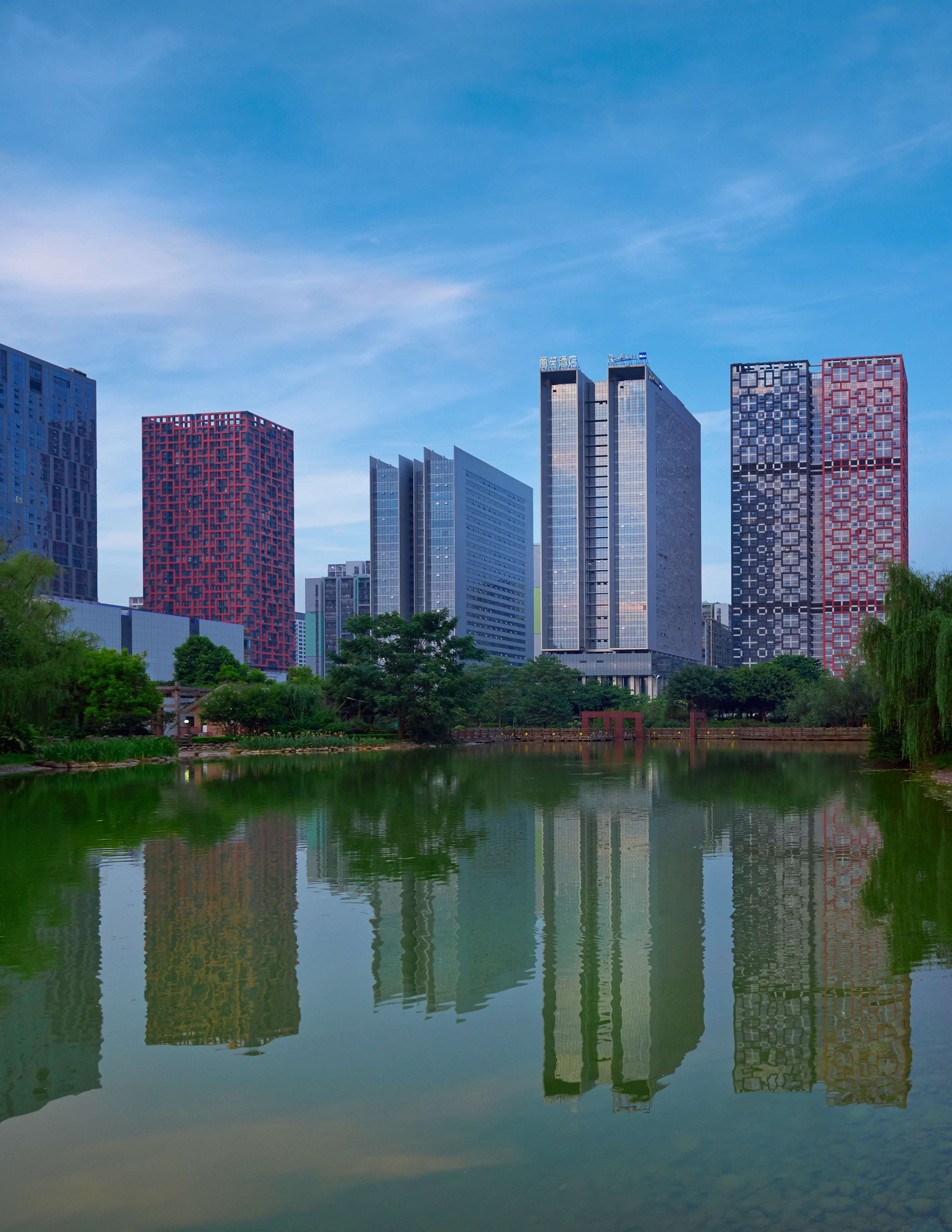 A cityscape with modern skyscrapers and a calm body of water reflecting the buildings.