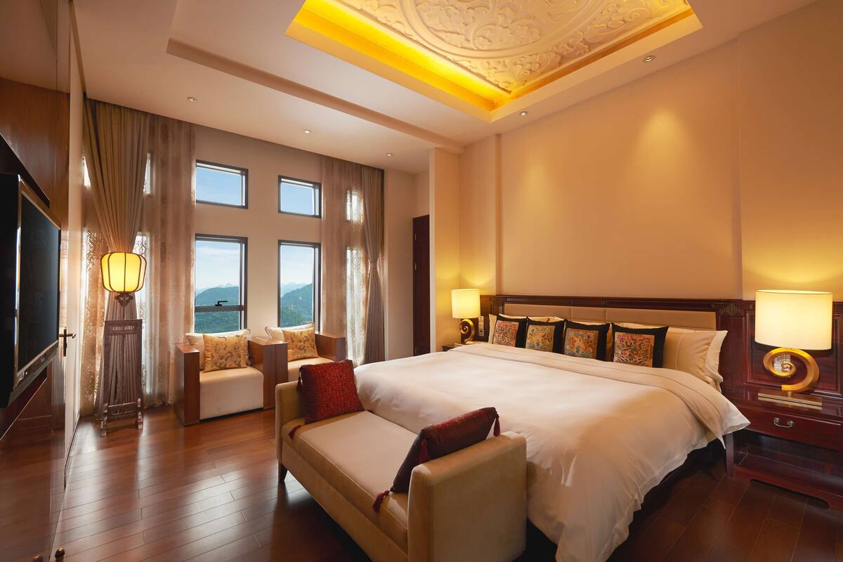 Ein geräumiges Hotelzimmer mit einem großen Bett, einer Sitzecke, einem Schreibtisch und Blick auf die Berge durch die Fenster.