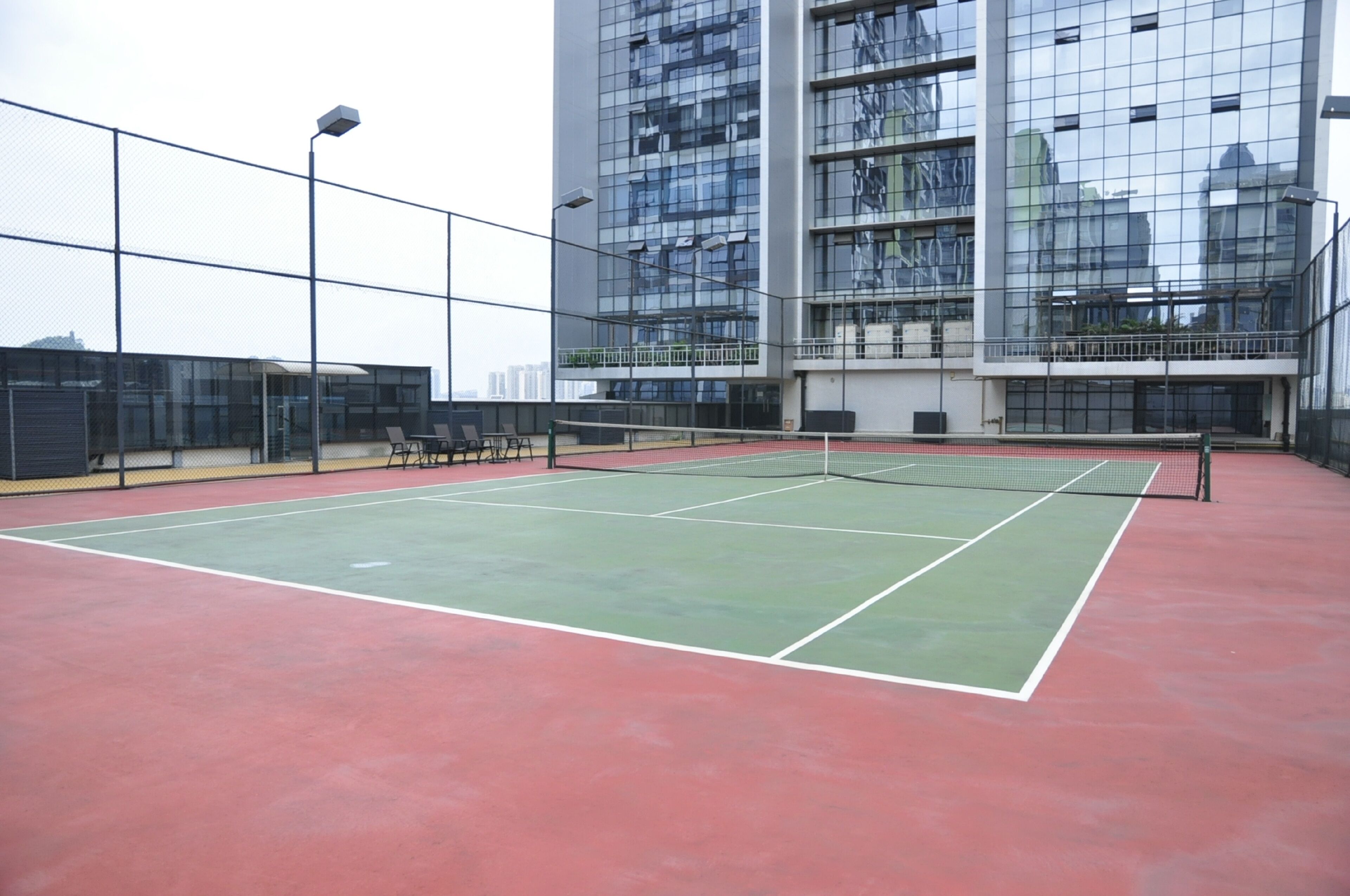 En indendørs tennisbane med net, omgivet af et hegn og bænke.