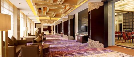 Un vestíbulo de hotel con un largo pasillo, una zona de estar y una sala de comedor.