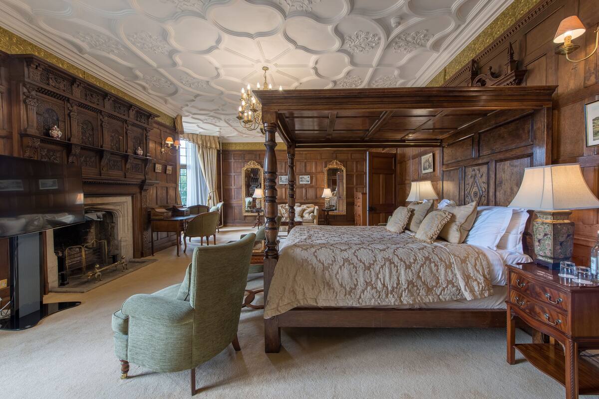 Une chambre à coucher de style traditionnel, avec un lit à baldaquin, une cheminée et un lustre.