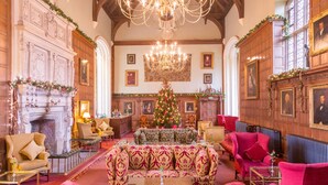 Una sala amplia con chimenea, un gran árbol de Navidad y una araña.