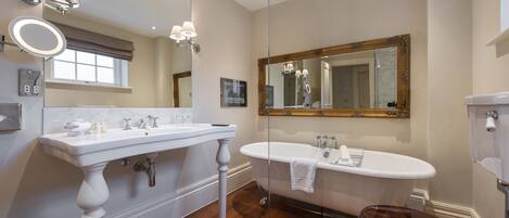 A bathroom with a white vanity, a freestanding bathtub, and a toilet.