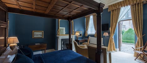 Un dormitorio con una cama grande, un escritorio, una silla, una chimenea y vistas al exterior.