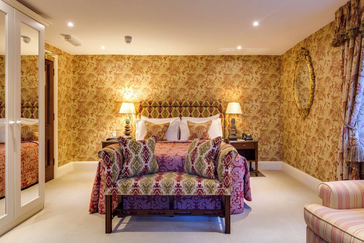 Une chambre à coucher avec un lit, deux tables de chevet, un canapé et un miroir.