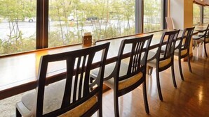 Un restaurant doté d’un long comptoir, de chaises et de grandes fenêtres équipées de stores.