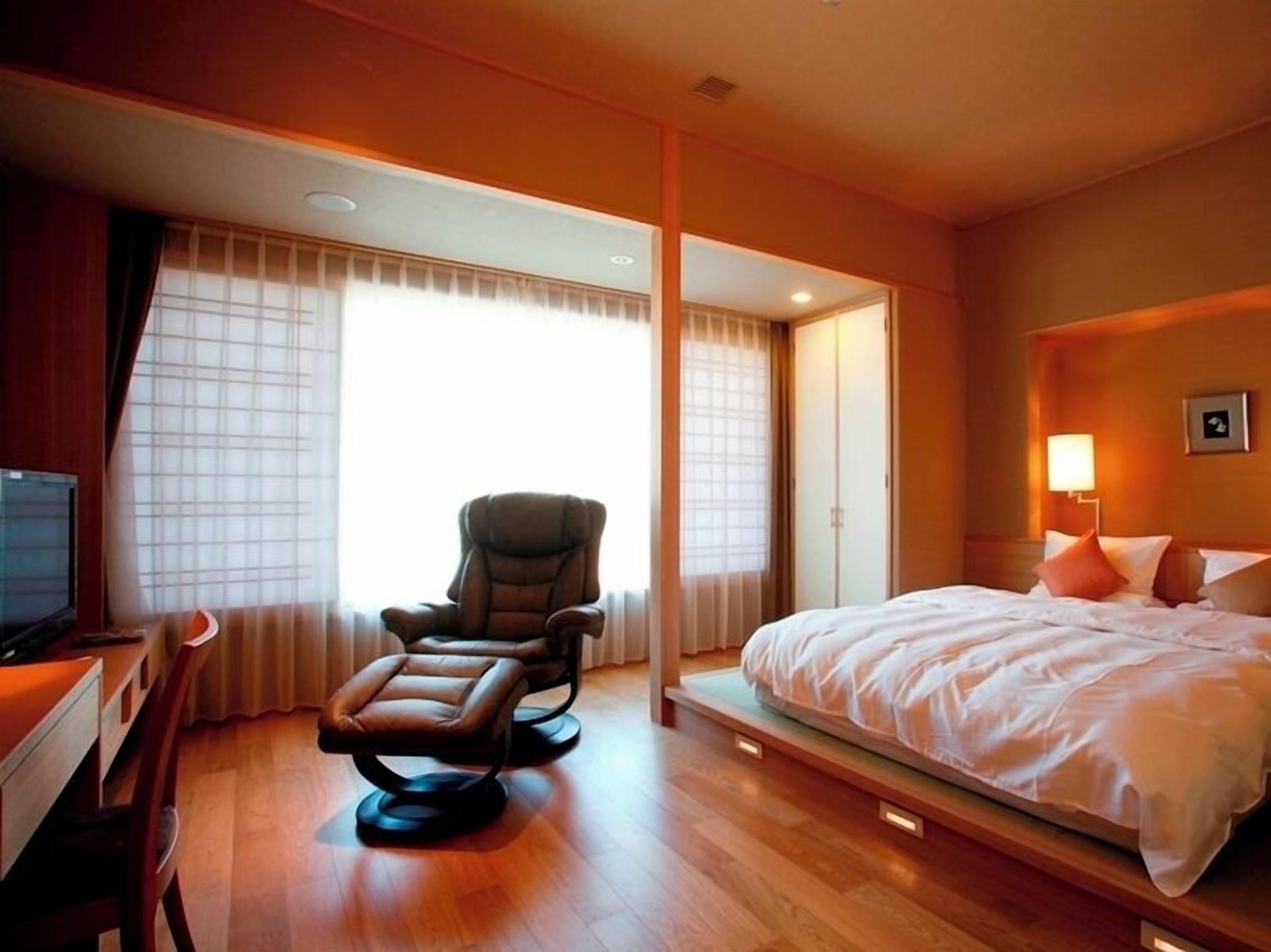 Une chambre d’hôtel avec un lit, une chaise, un bureau et un téléviseur.
