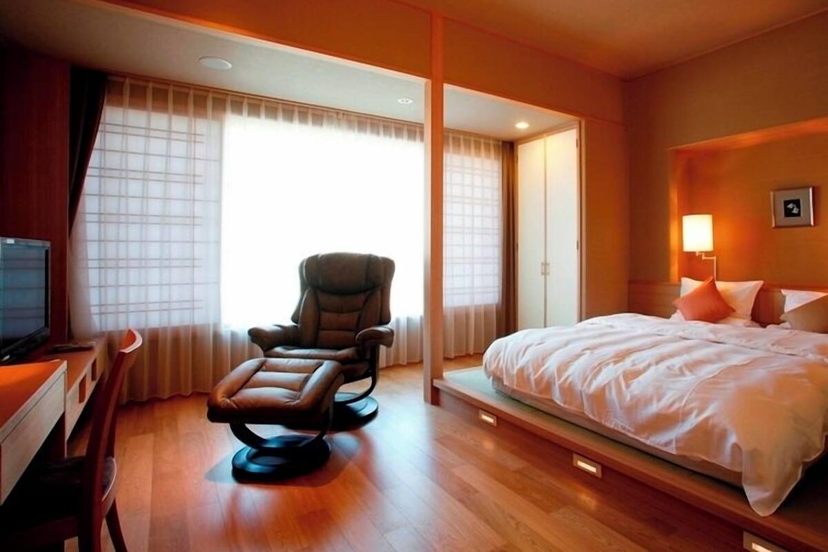 Une chambre d’hôtel avec un lit, une chaise, un bureau et un téléviseur.