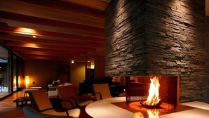 A modern interior with a stone wall, a round table with chairs, and a fireplace.