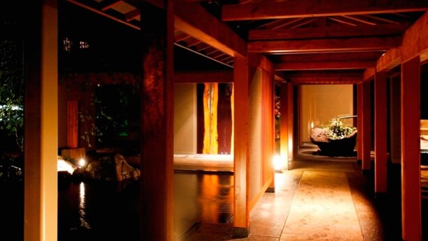 A corridor with wooden beams, a stone wall, and a water feature.