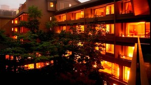 A multi-story hotel with balconies, large windows, and a view of trees.
