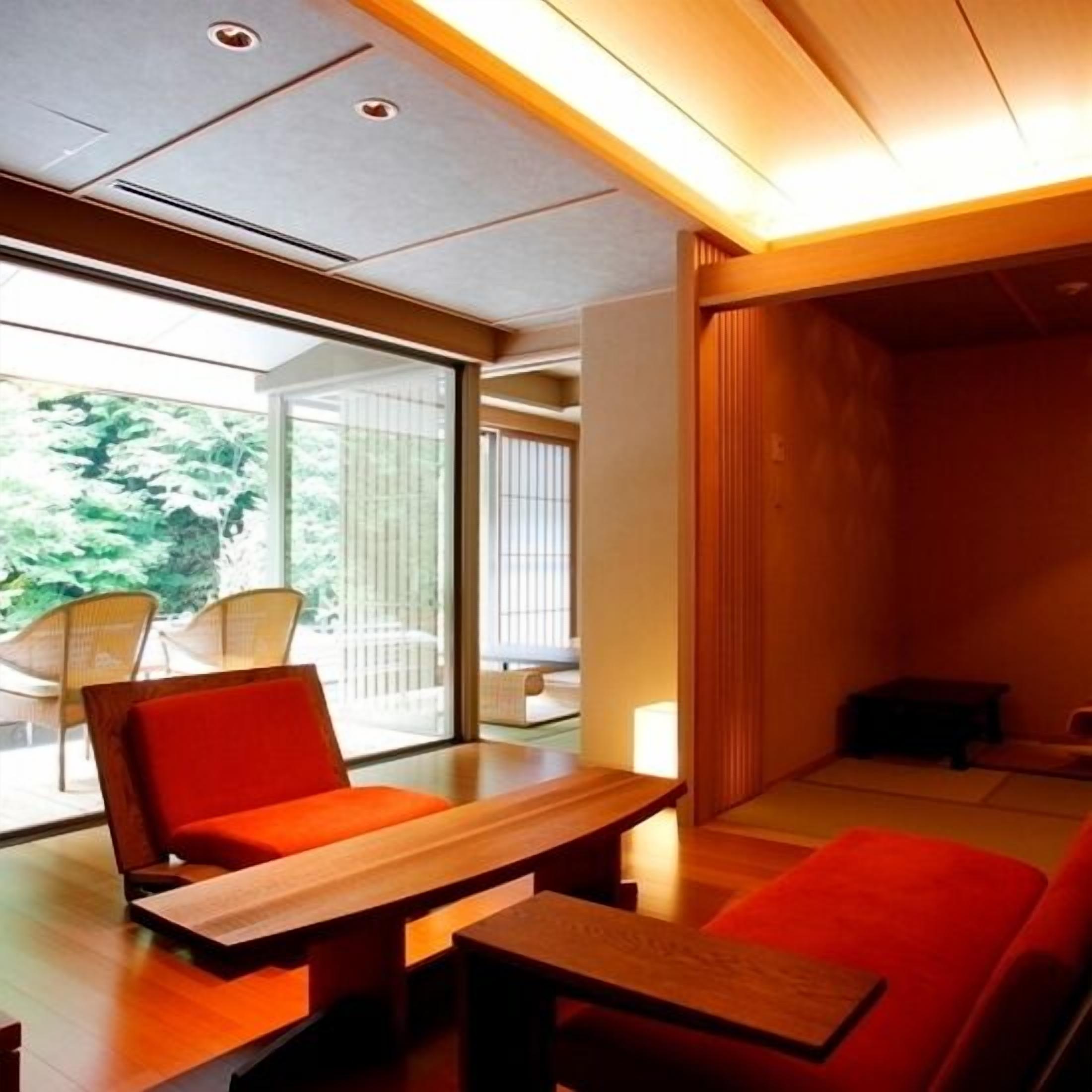 A modern interior with a wooden table, red seating, and large windows.
