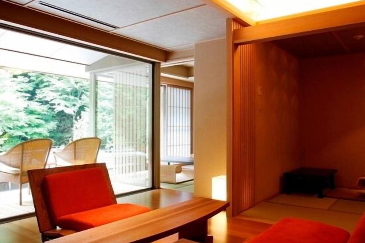 Un intérieur moderne avec une table en bois, des sièges rouges et de grandes fenêtres.