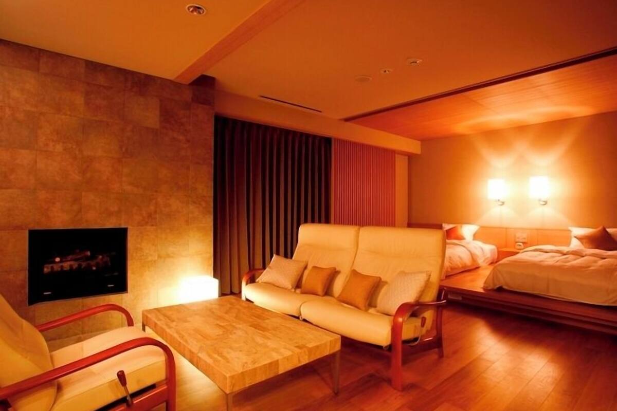 Une chambre d’hôtel équipée d’un canapé, d’une table basse, d’un téléviseur, d’un lit et d’une lampe fixée au mur.