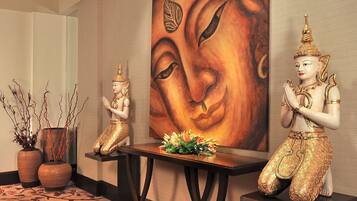 Un área de recepción con dos estatuas, una pintura de Buda y una mesa con flores.