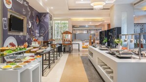 A buffet area with various food stations, a television, and a kitchen in the background. - Radisson Hyderabad Hitec City (Hyderabad)
