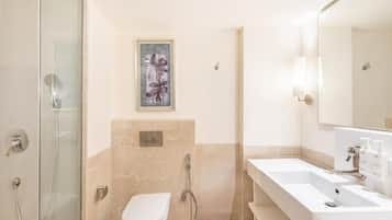 A modern bathroom with a glass shower enclosure, a toilet, a double sink vanity, and a framed artwork on the wall.