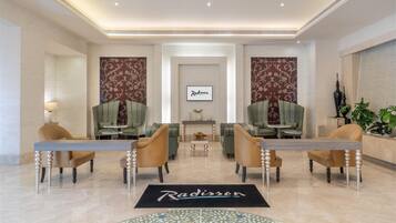 A hotel lobby with a reception desk, two sofas, a coffee table, and a fireplace.