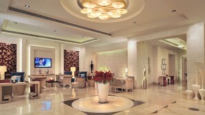 A spacious lobby with a central floral arrangement, comfortable seating, a television, and modern decor. - Radisson Hyderabad Hitec City (Hyderabad)