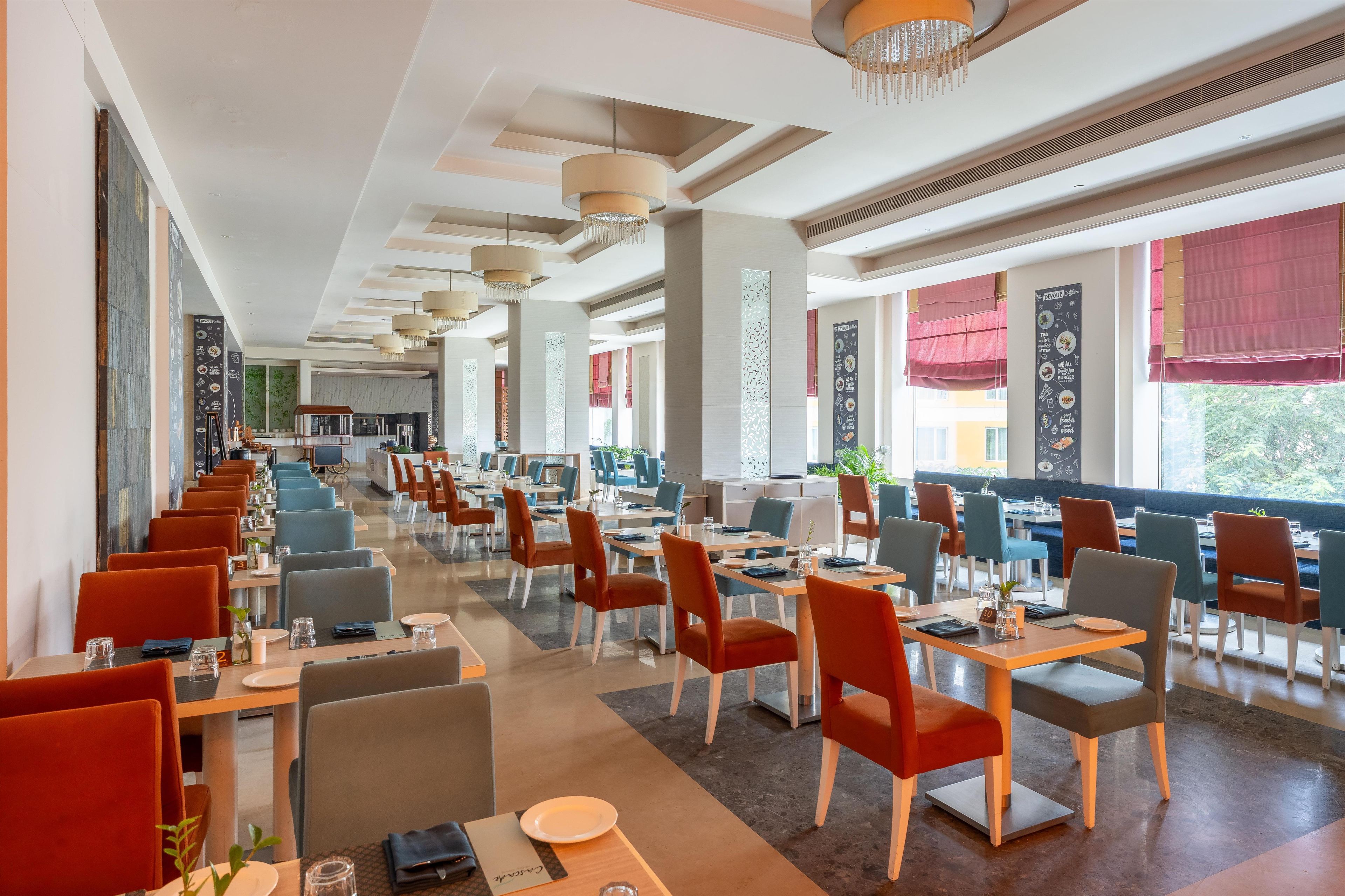 Un restaurante espacioso con techos altos, iluminación moderna y diversas opciones de asientos.