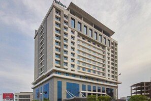 A multi-story hotel with a modern design, featuring a prominent entrance and a large glass facade. - Radisson Hyderabad Hitec City (Hyderabad)