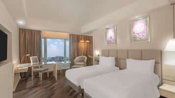 Une chambre d’hôtel avec deux lits, un bureau, une chaise et une vue sur la ville.