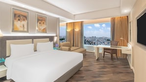 A hotel room with a large bed, a desk, a chair, and a view of a cityscape. - Radisson Hyderabad Hitec City (Hyderabad)