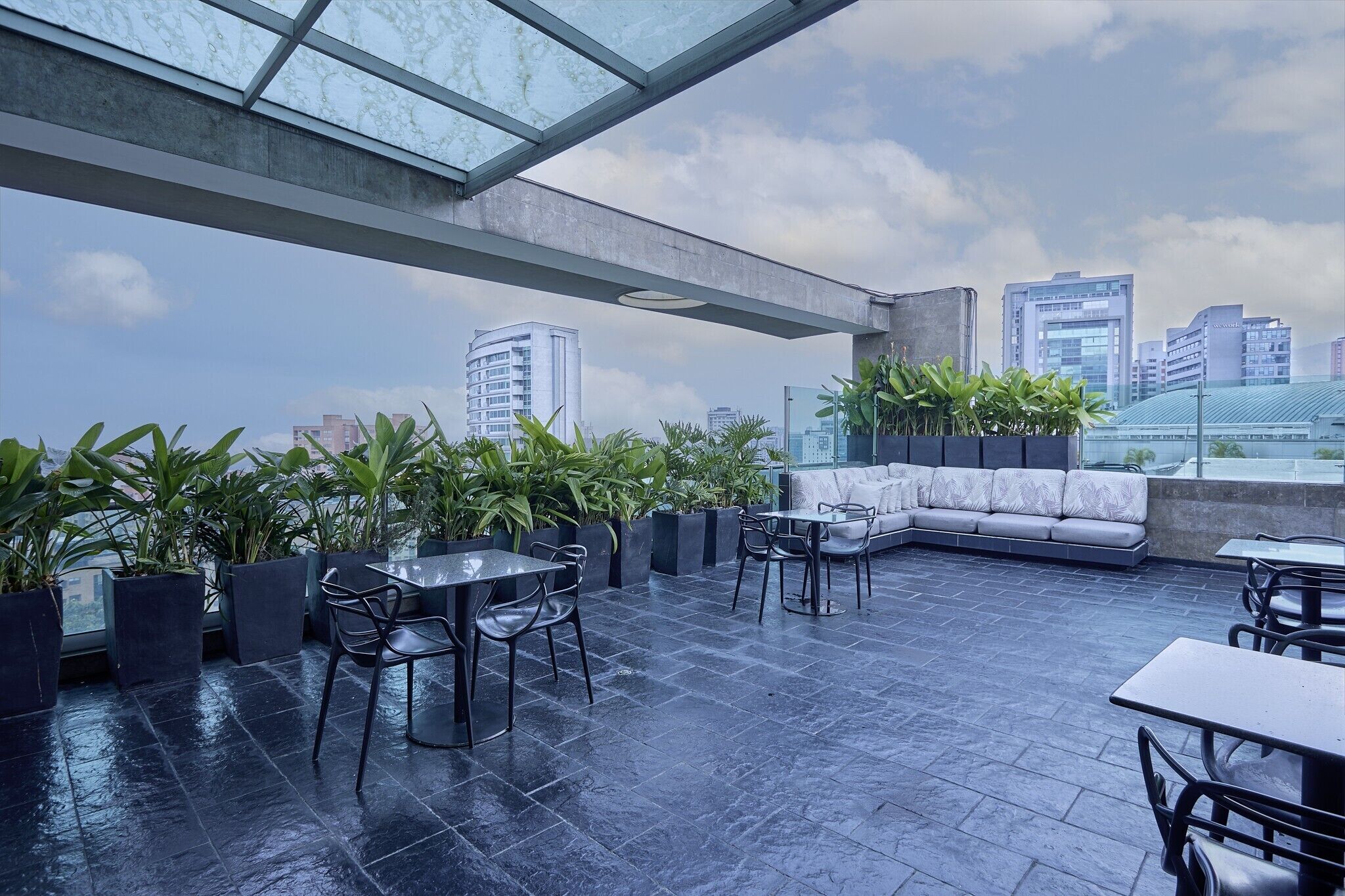 A rooftop terrace with a seating area, tables, and potted plants.