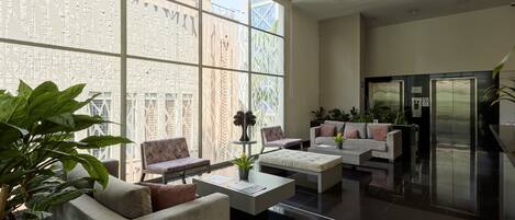 Un vestíbulo moderno con zona de estar, mostrador de recepción y un amplio ventanal con vistas a la ciudad.