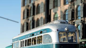 A vintage train with a blue and white color scheme parked in front of a large building with multiple windows.
