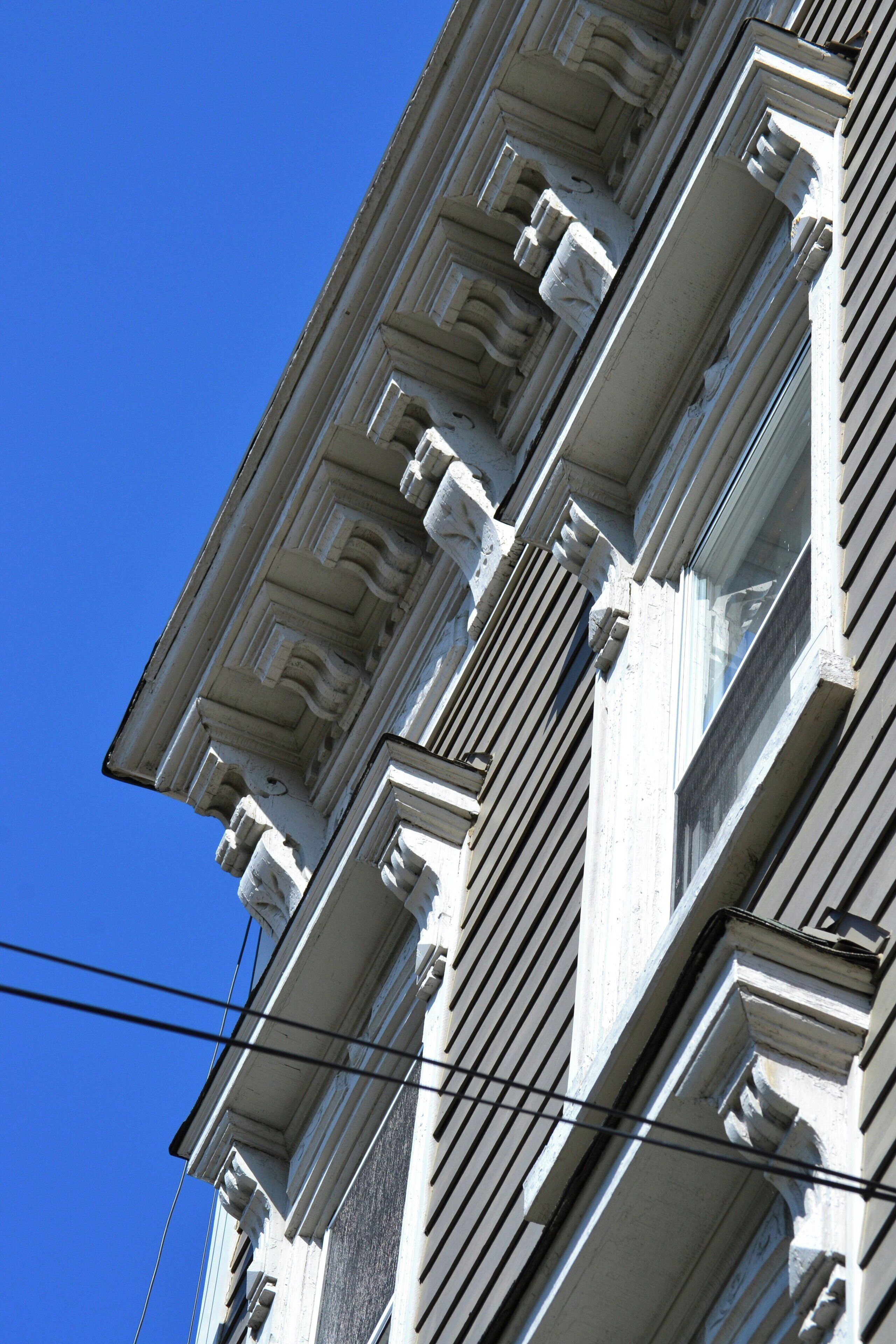 A corner of a building with classical architectural details, including ornate cornices and a symmetrical window design.