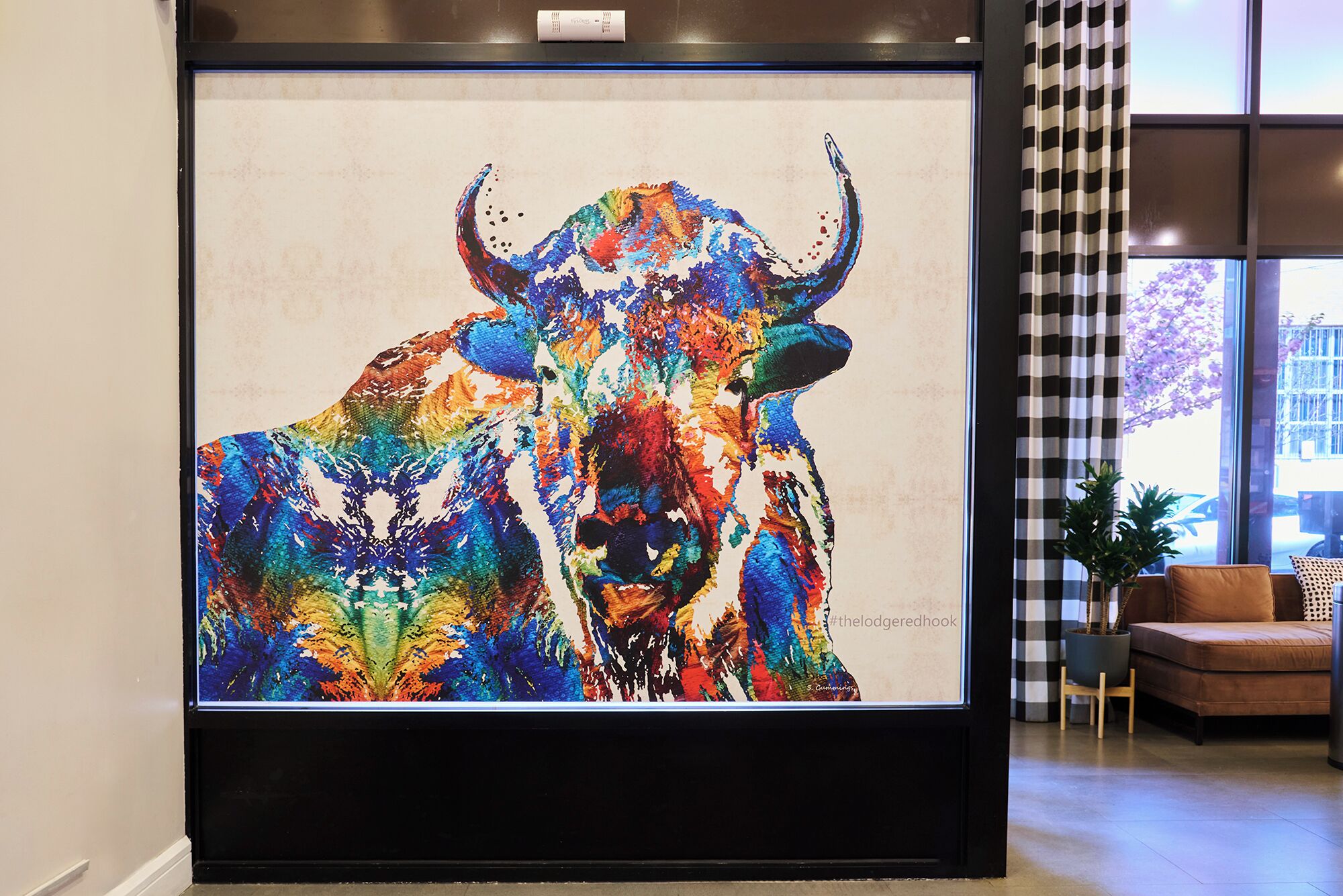 Una obra de arte enmarco que muestra un toro colorido en un ambiente interior moderno.